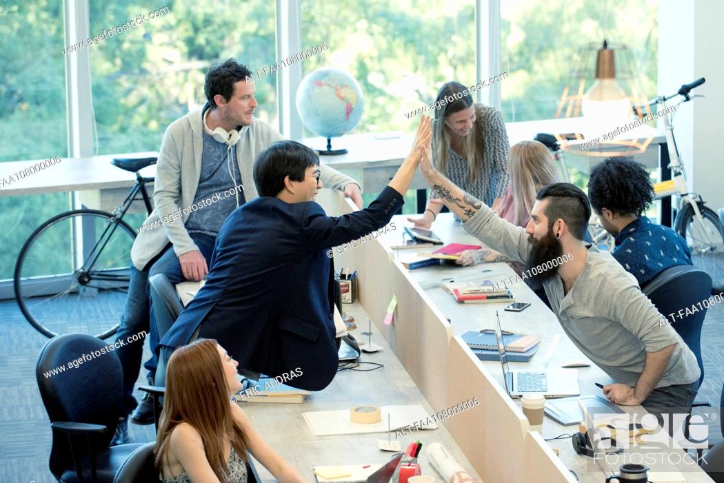 Stock Photo: Colleagues high-fiving in casual office.