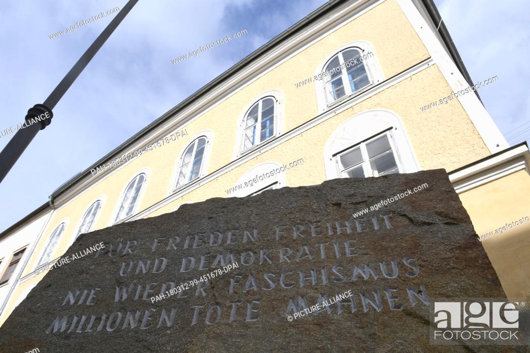 Stock Photo: 12 March 2018, Germany, Braunau: A memorial stone against war and fascism in front of Adolf Hitler's birth house. Clouds and sun appear above the border town.