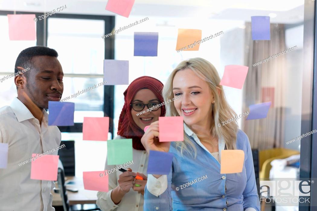 Stock Photo: young creative startup business people on meeting at modern office making plans and projects with post stickers on glass.