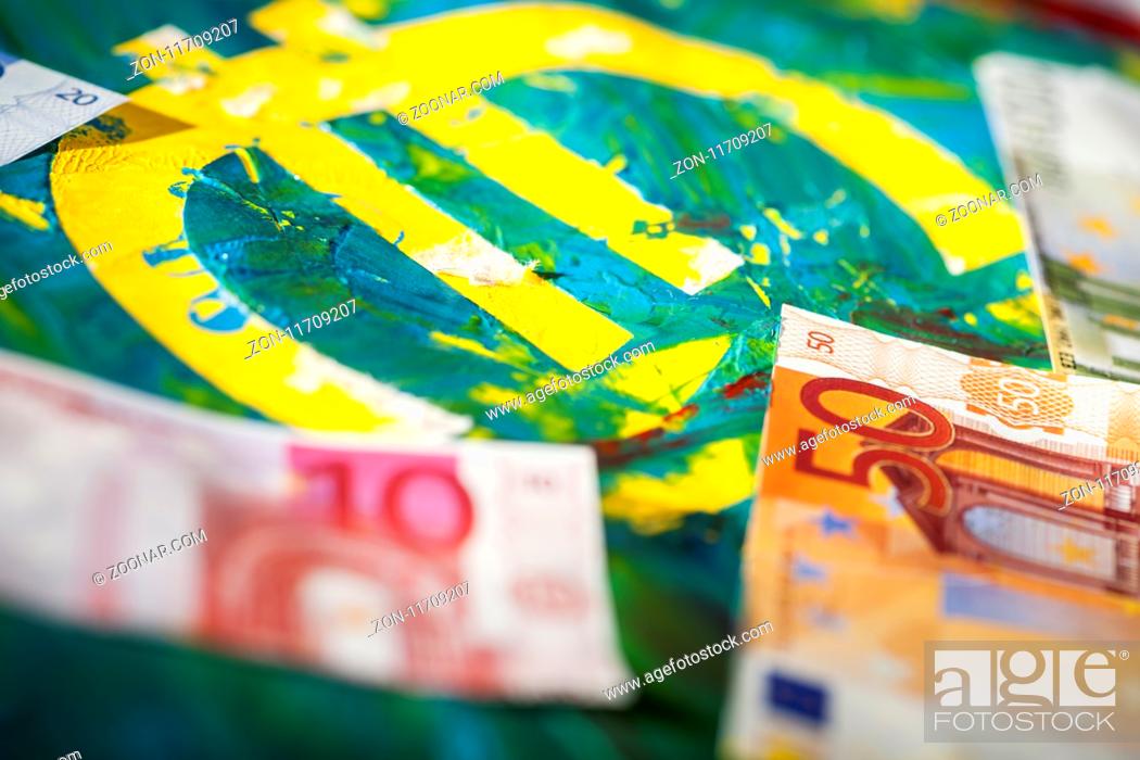 Stock Photo: Flachwinkel-Ansicht eines Euro-Zeichens in bunter pastös vermischter Acryl-Farbe mit aufgelegten Euro-Banknoten. Low angle view of a euro sign in colorful pasty.