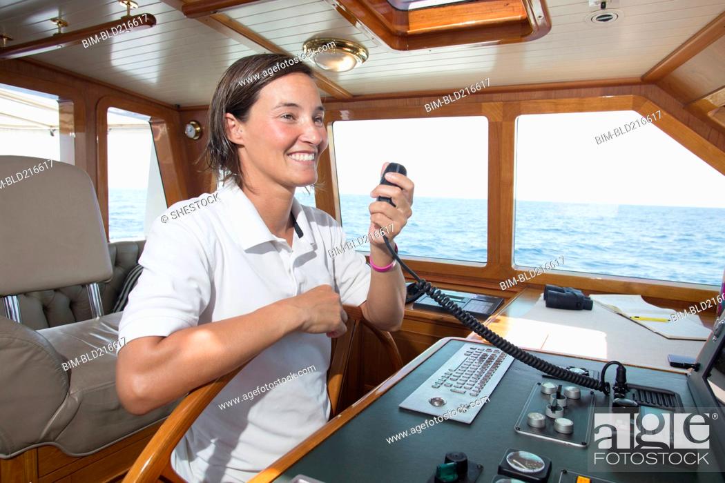 Stock Photo: Caucasian woman steering boat and using radio.