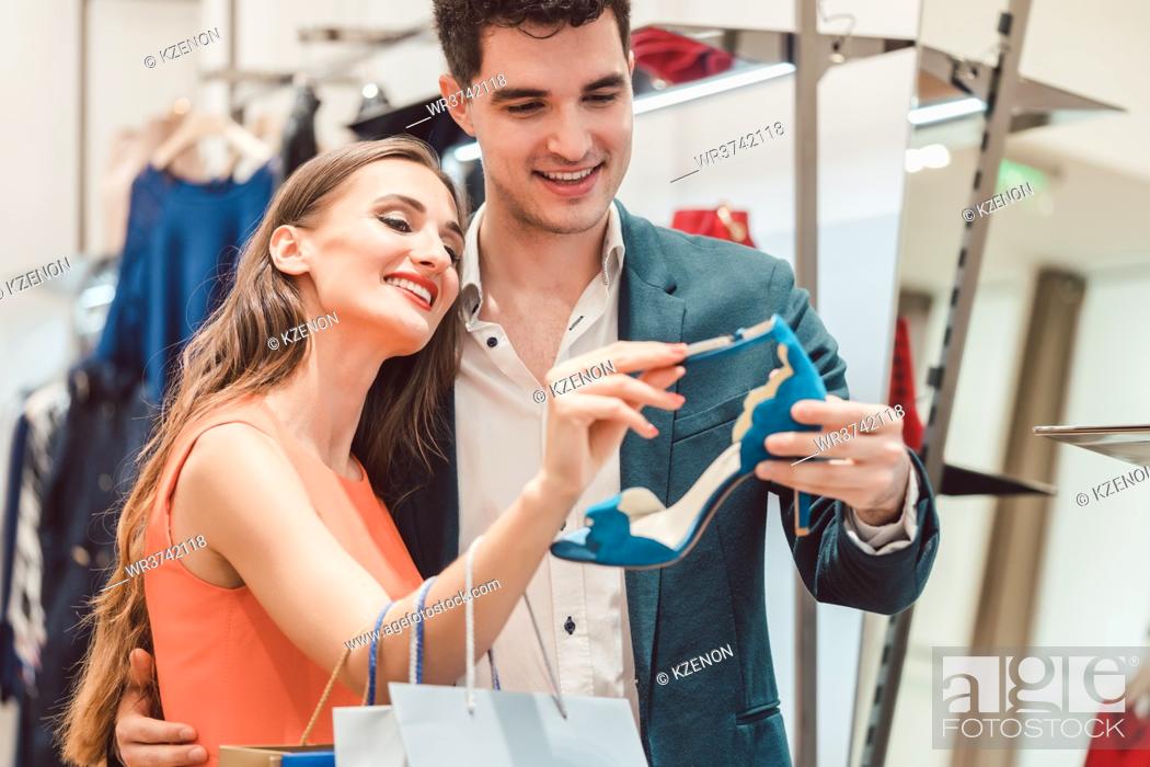 Stock Photo: Woman with her man looking at blue shoes in store wanting them badly.