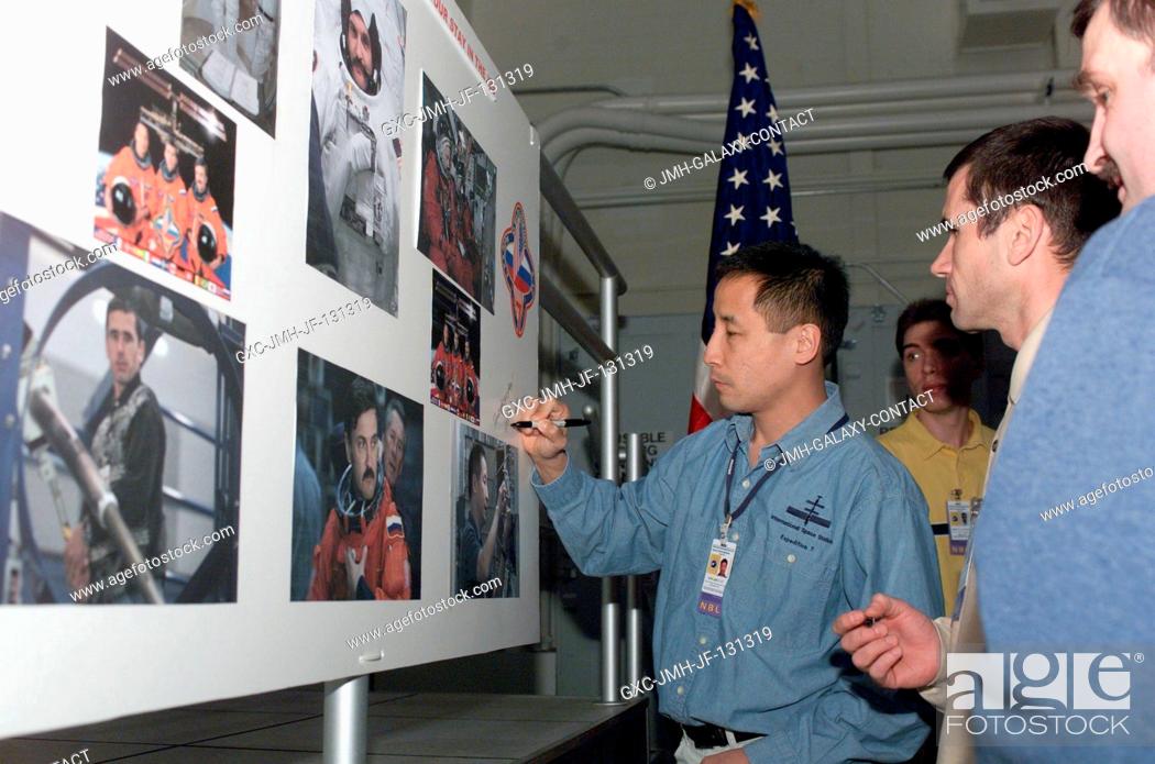 Stock Photo: Astronaut Edward T. Lu, Expedition Seven NASA ISS science officer, signs a mission collage during a cake-cutting ceremony in the Jake Garn Simulation and.