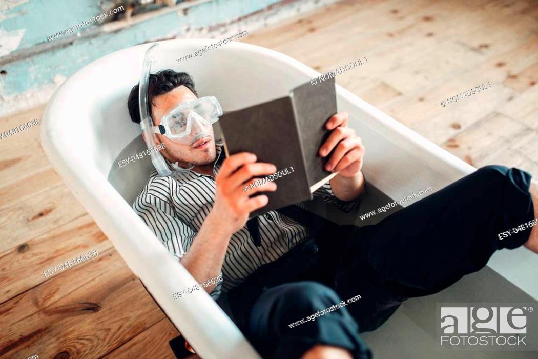 Stock Photo: Funny businessman in flippers and mask lies in bathtub and reads a book, humor. Business lottery concept.