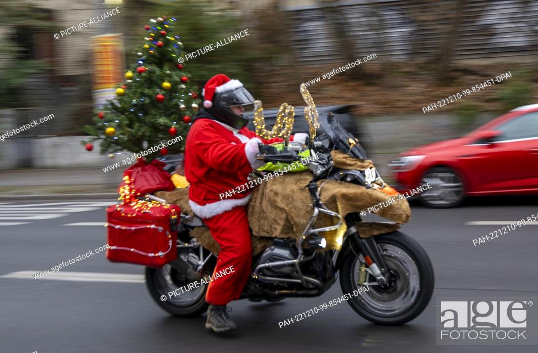 Stock Photo: 10 December 2022, Berlin: A participant in the ""Santa Claus on Road"" campaign rides through the city on a motorcycle decorated for Christmas.