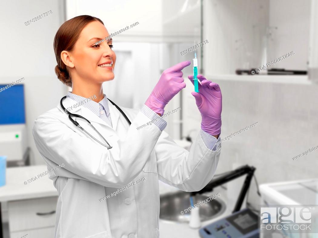 Stock Photo: happy female doctor with syringe at hospital.