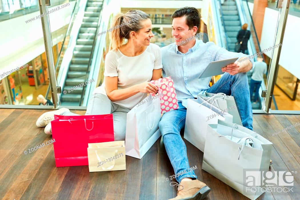 Stock Photo: Junges Paar mit vielen Einkaufstüten im Einkaufszentrum macht Pause vom Shopping.