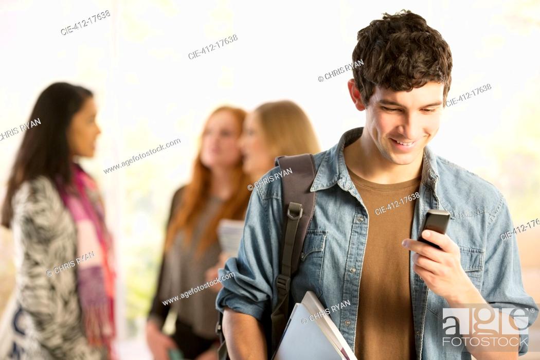 Stock Photo: College student text messaging with cell phone.