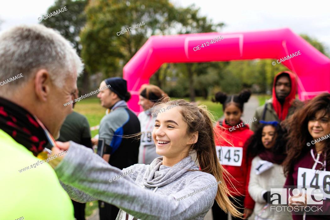 Stock Photo: Daughter placing medal around neck of father at charity run.