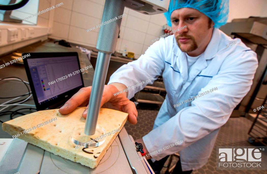 Stock Photo: Development engineer Kai Gajewski tests the crunchiness of a freshly baked pizza crust in the new Technology Center at the pizza factory of the Dr.