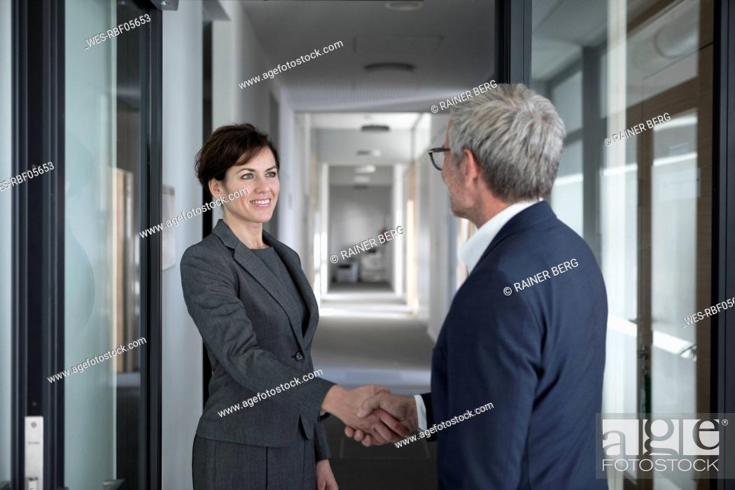 Stock Photo: Businessman and businesswoman shaking hands in office.