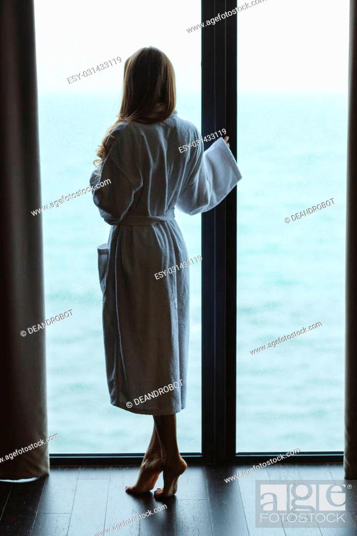Stock Photo: Back view of beautiful slim female standing near the panoramic window.