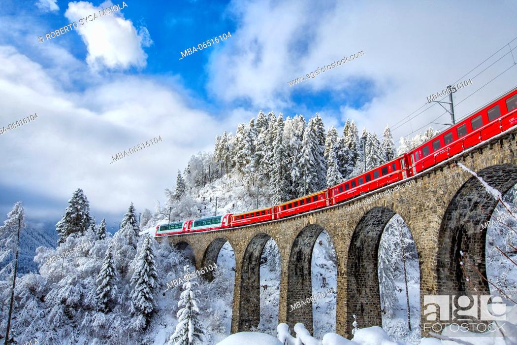 Imagen: Bernina Express passes through the snowy woods around Filisur Canton of Grisons Switzerland Europe.