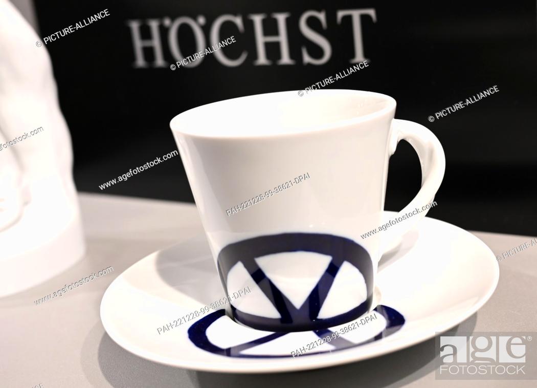 Imagen: 28 December 2022, Hessen, Frankfurt/Main: Cup and saucer from the Höchst porcelain manufactory stand in front of the manufactory's logo in the factory outlet.