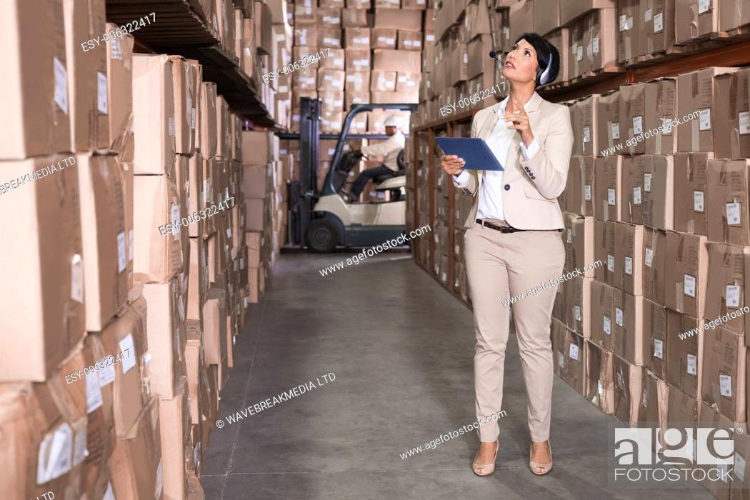 Photo de stock: Pretty warehouse manager using tablet pc in a large warehouse.