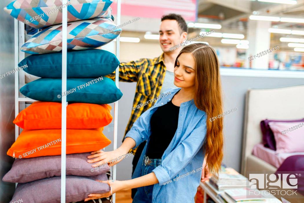Imagen: Young love couple holds pillows in furniture store. Man and woman looking samples for bedroom in shop, husband and wife buys goods for modern home interior.