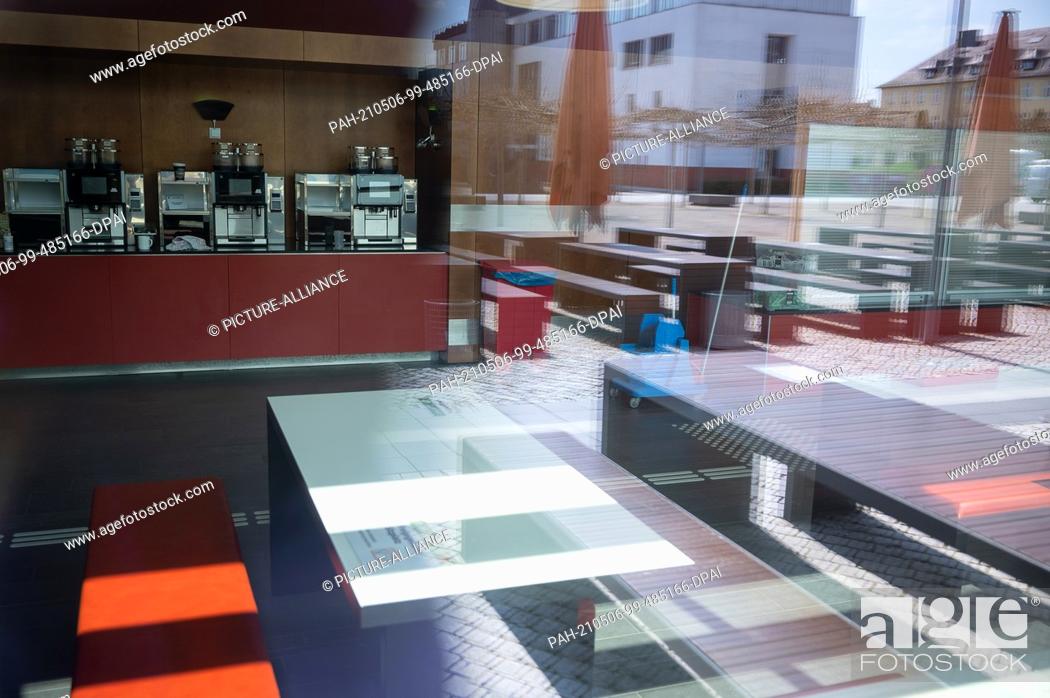 Stock Photo: PRODUCTION - 28 April 2021, Hessen, Fulda: The outside of the canteen at Fulda University of Applied Sciences is reflected in its glass.