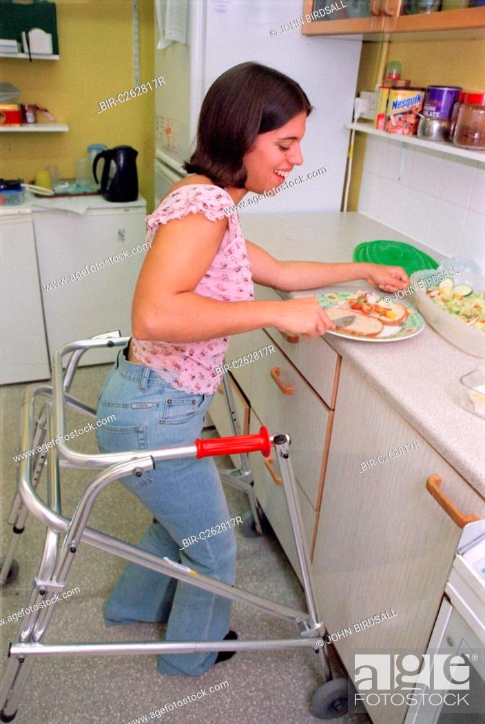 Stock Photo: Teenage girl with physical disability preparing sandwich in kitchen of residential respite care home,.