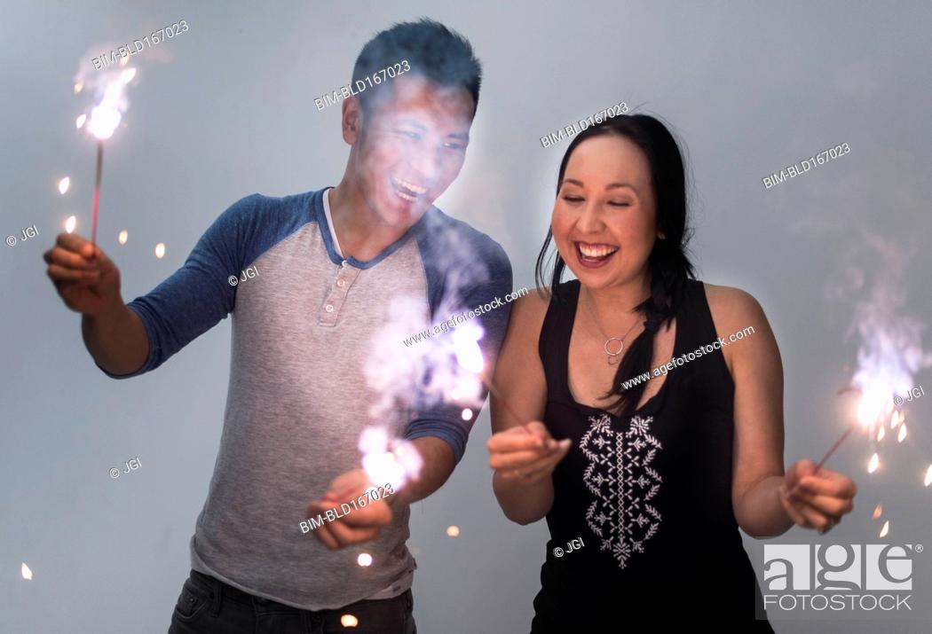 Stock Photo: Smiling couple playing with sparklers.