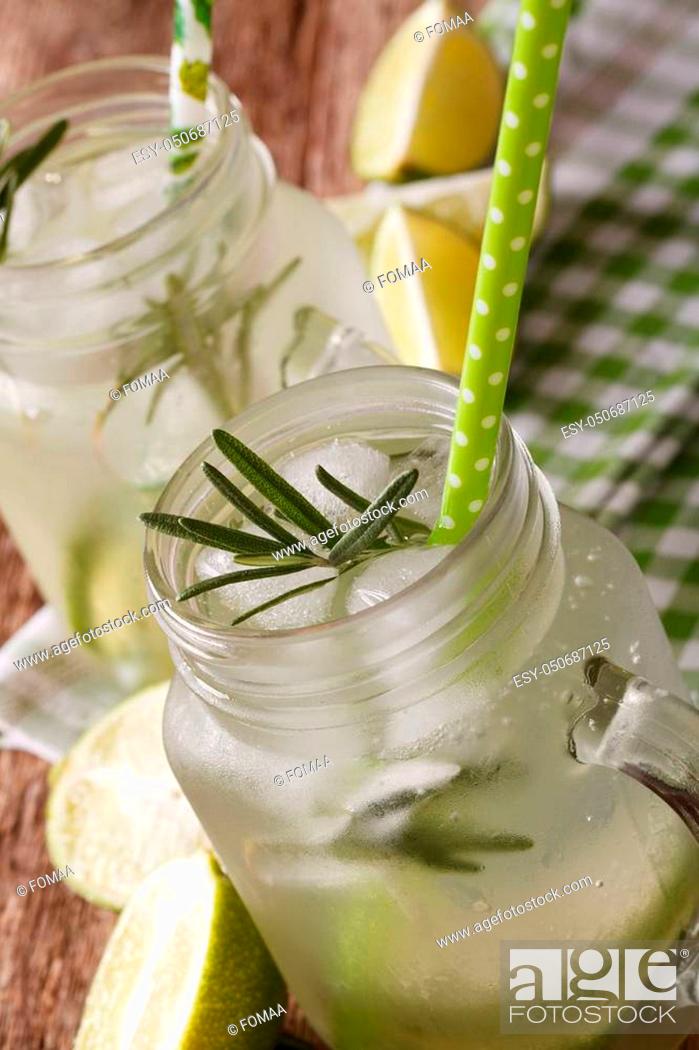 Stock Photo: Refreshing drink with lime, ice and rosemary macro in a glass jar on the table. vertical.