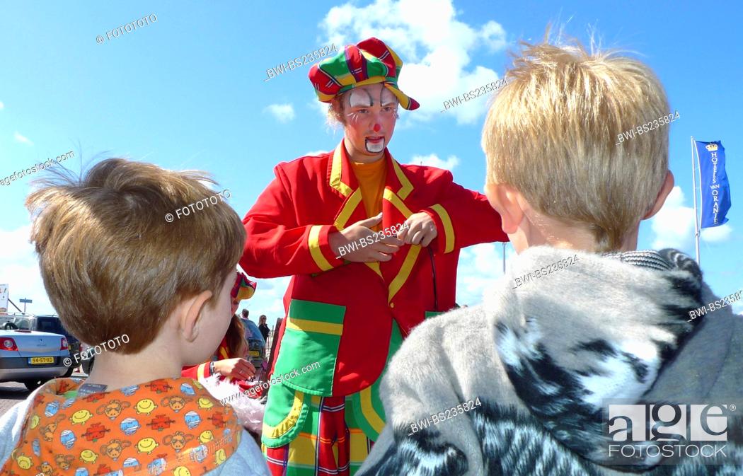 Stock Photo: colourful clothed street clown joking, children watching him, Netherlands, Noordwijk.