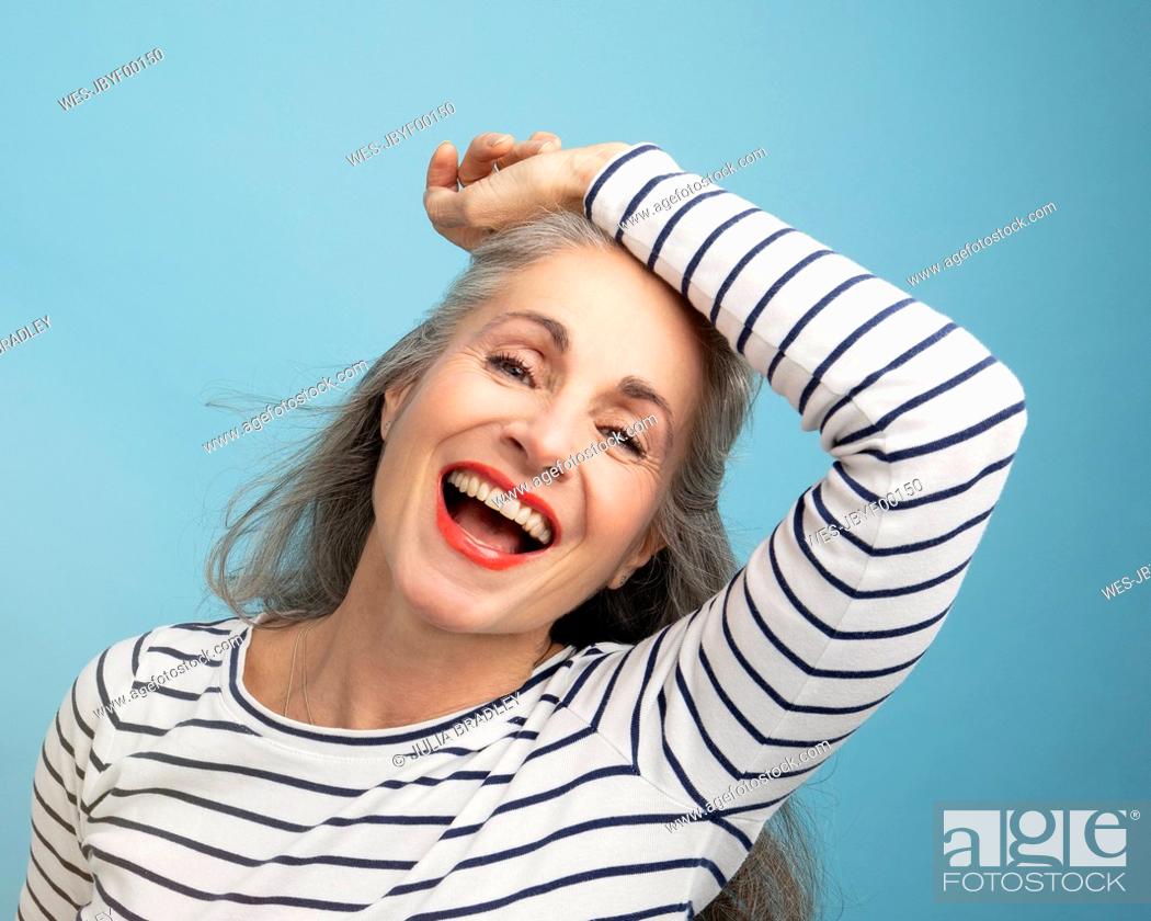 Stock Photo: Happy woman with hand on head against blue background.