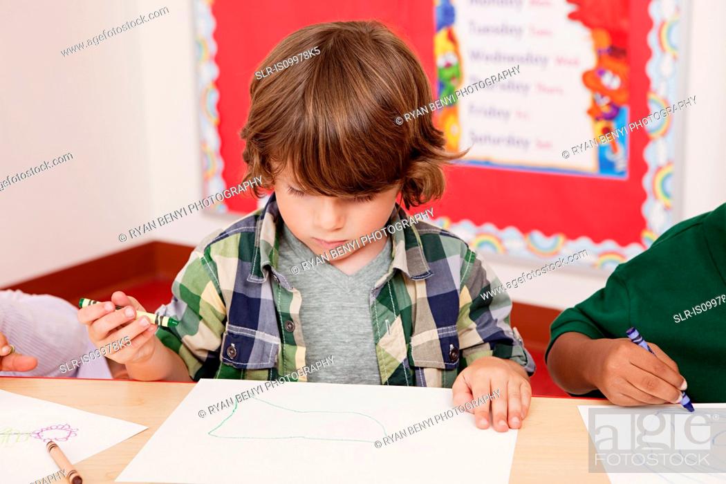 Stock Photo: Boy drawing a picture in class.