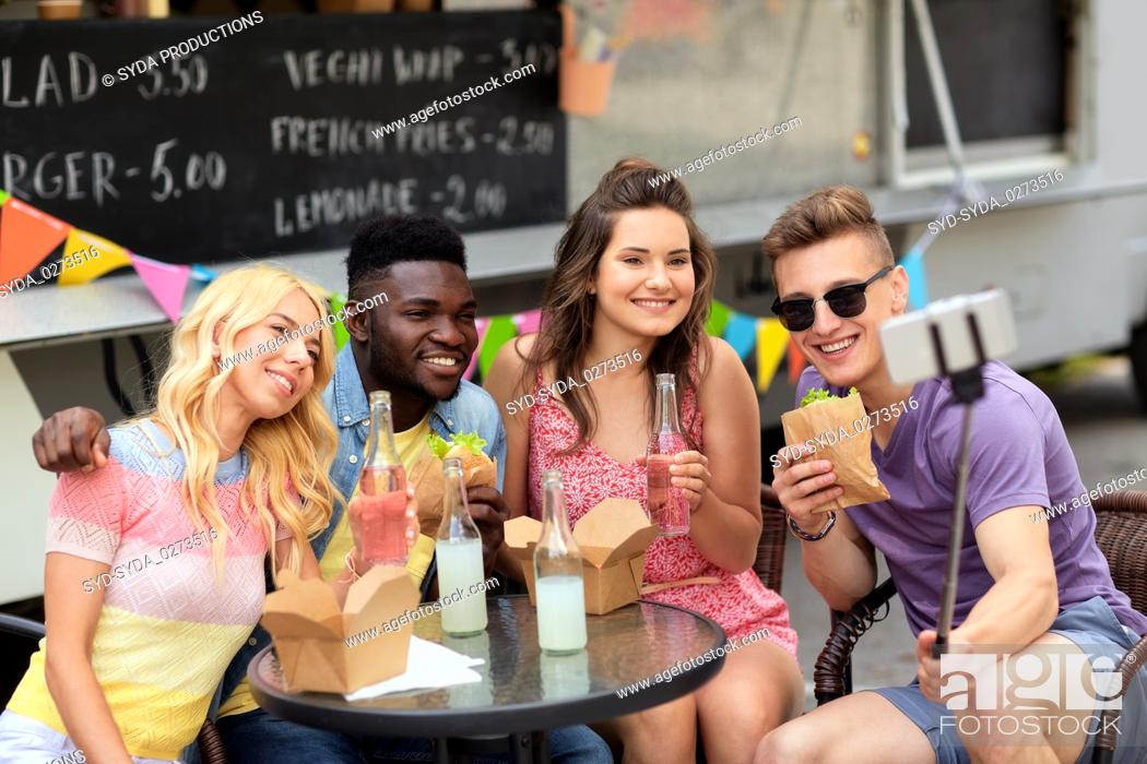 Stock Photo: happy young friends taking selfie at food truck.
