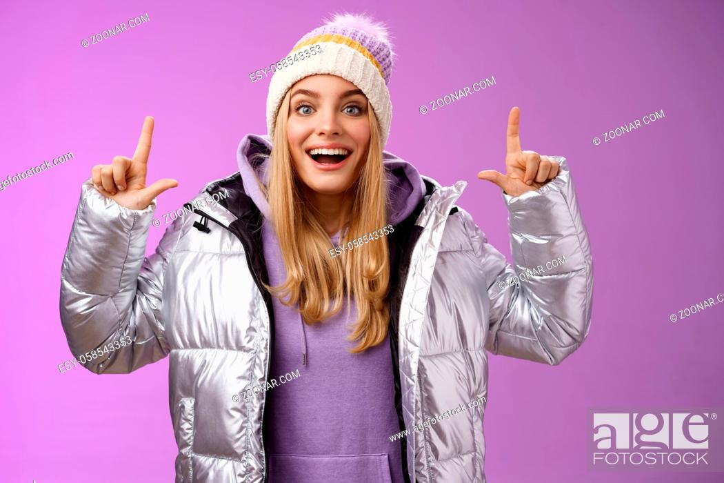 Stock Photo: Lifestyle. Excited carefree cheerful fair-haired european girl in silver jacket winter hat raising hands pointing up have excellent idea smiling broadly.