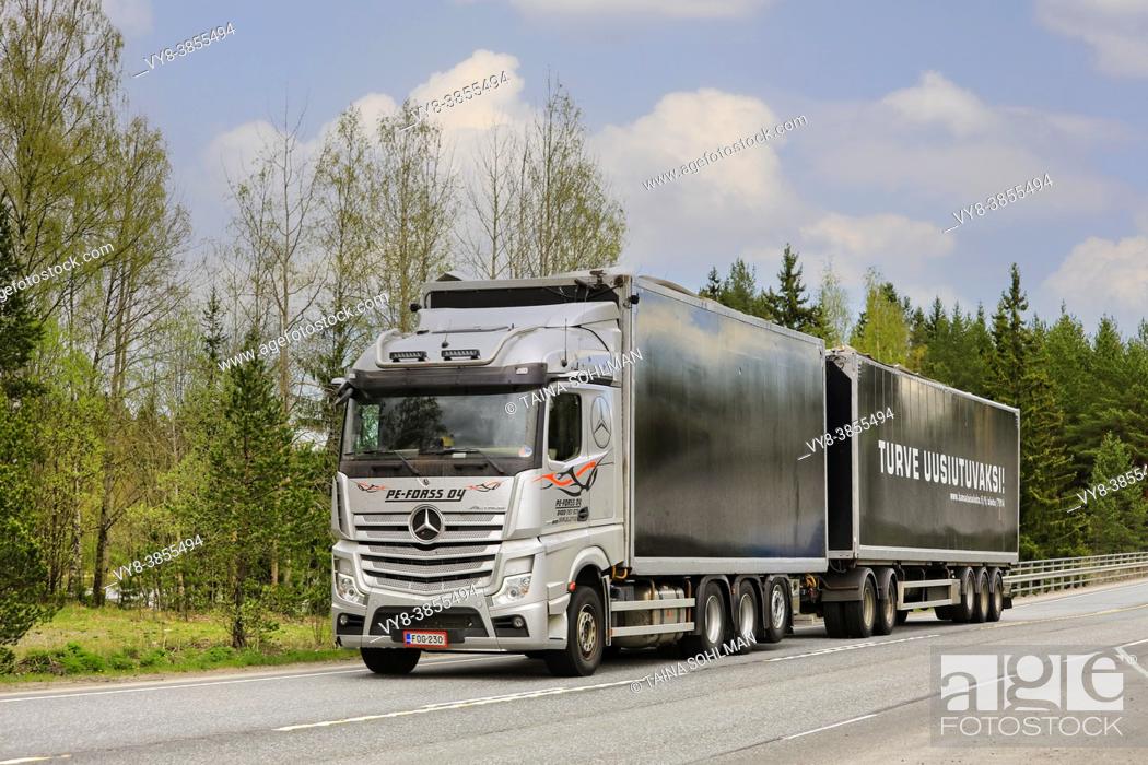 Stock Photo: Silver Mercedes-Benz Actros truck of PE-Forss Oy pulls peat transport trailer on highway 2 on day of spring. Forssa, Finland. May 14, 2021.
