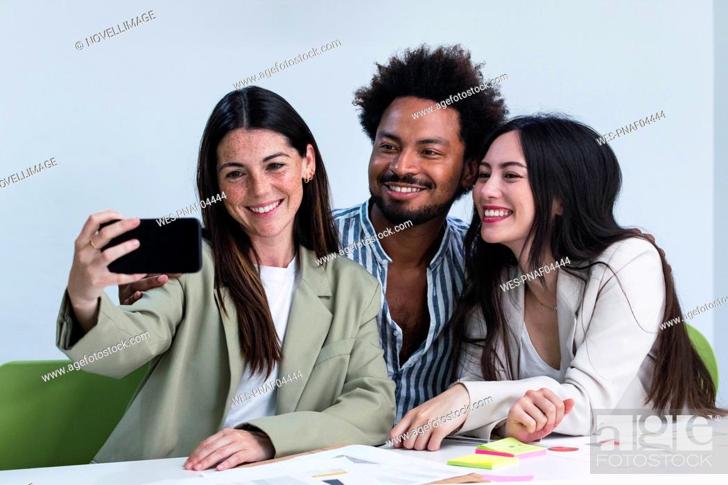 Stock Photo: Happy colleagues taking a selfie in office.