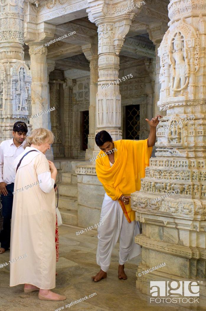 Stock Photo: Temple priest shows tourists stone carving detail at The Ranakpur Jain Temple at Desuri Tehsil in Pali District of Rajasthan, India.