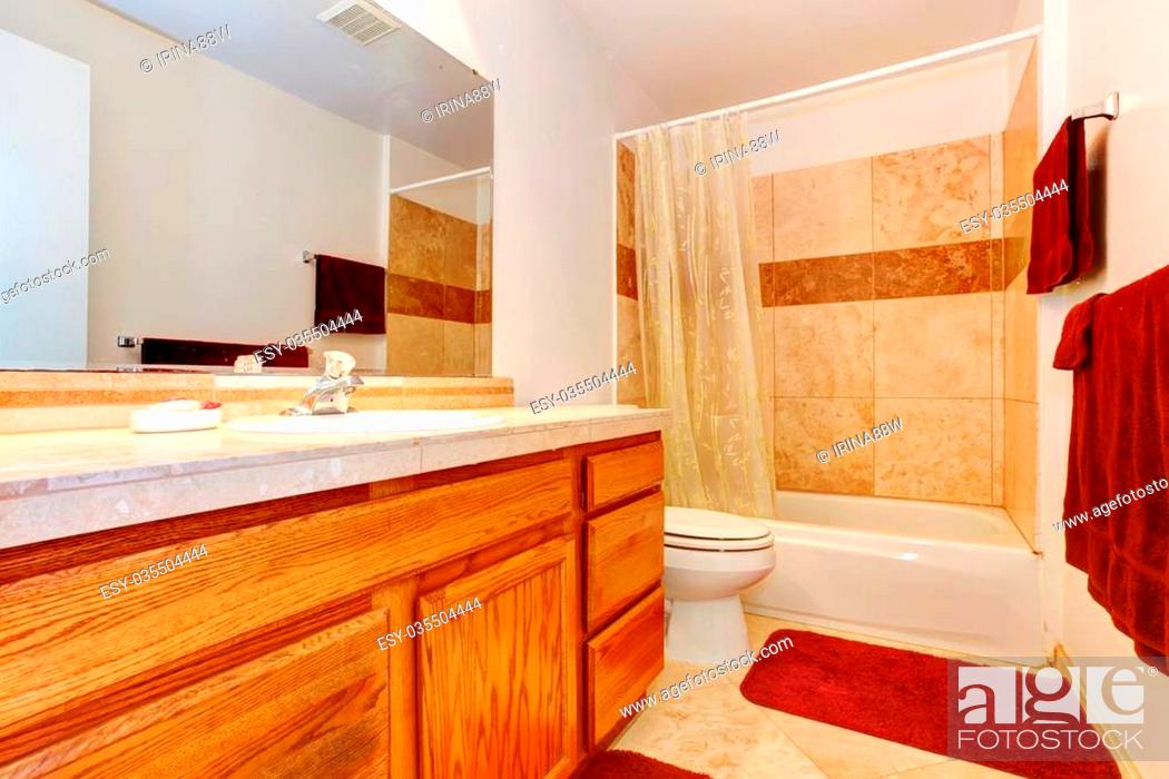 Beige Bathroom With Tile Floor Wooden Cabinets Red Towels Red