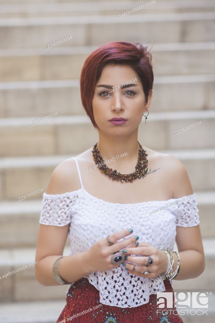 Stock Photo: Beautiful young woman with short red hair outdoors.
