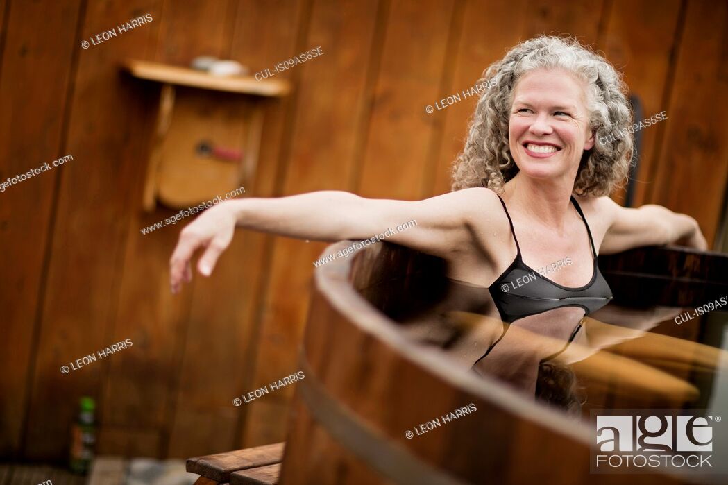 Stock Photo: Smiling mature woman in hot tub at eco retreat.