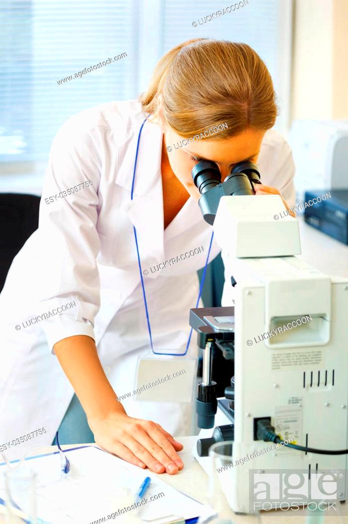 Stock Photo: Beautiful woman in a laboratory working with a microscope.