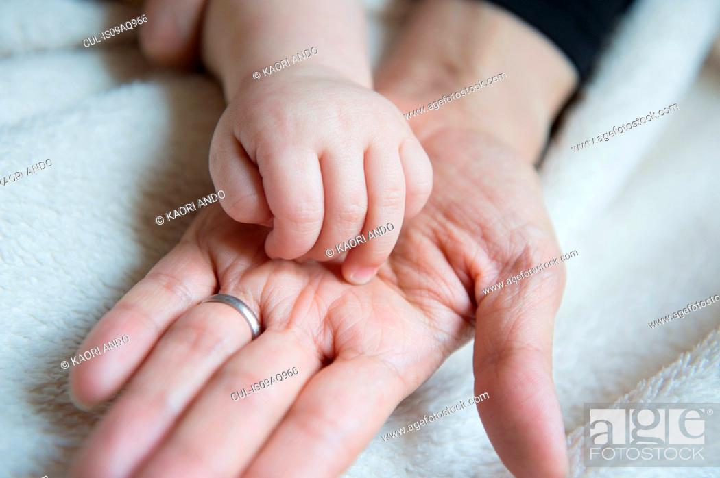 Stock Photo: Baby boy's hand resting on mother's hand, close-up.