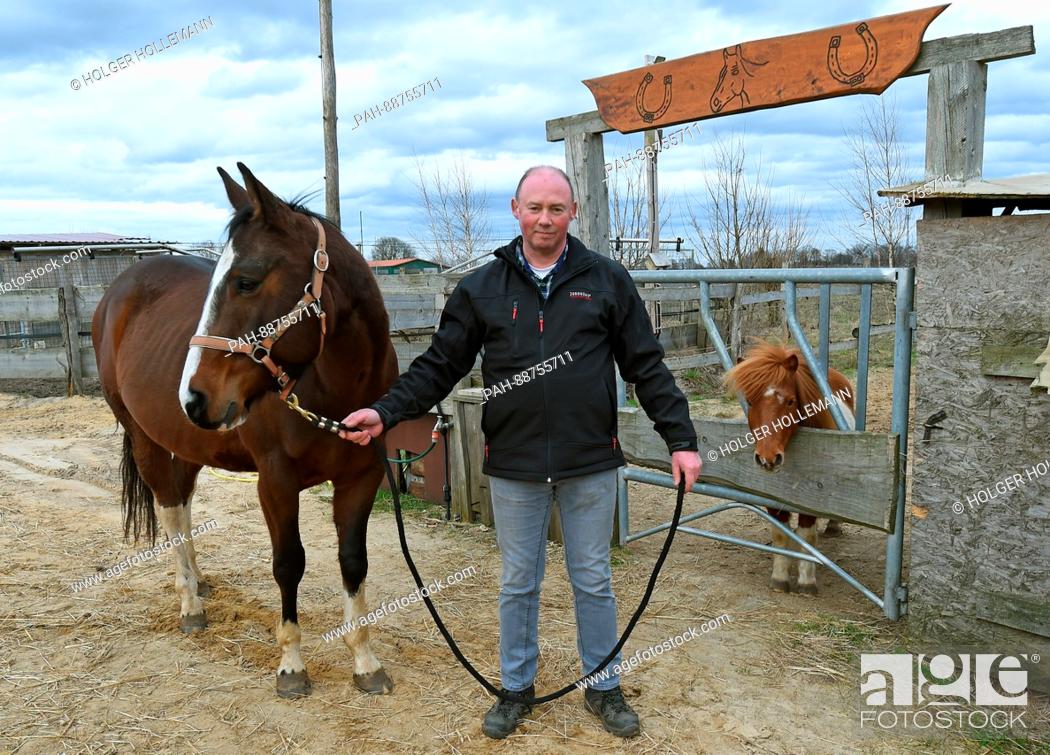 Photo de stock: Farmer Andreas Strahlmann stands next to his gelding Santos at his farm in Wettmar, Germany, 28 February 2017. 60 horses live in the horse boxes he rents out to.