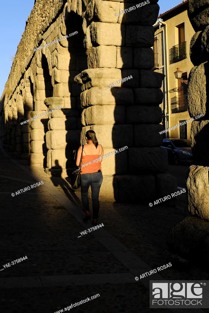 Stock Photo: A woman walking next to the start of the acqueduct of Segovia.