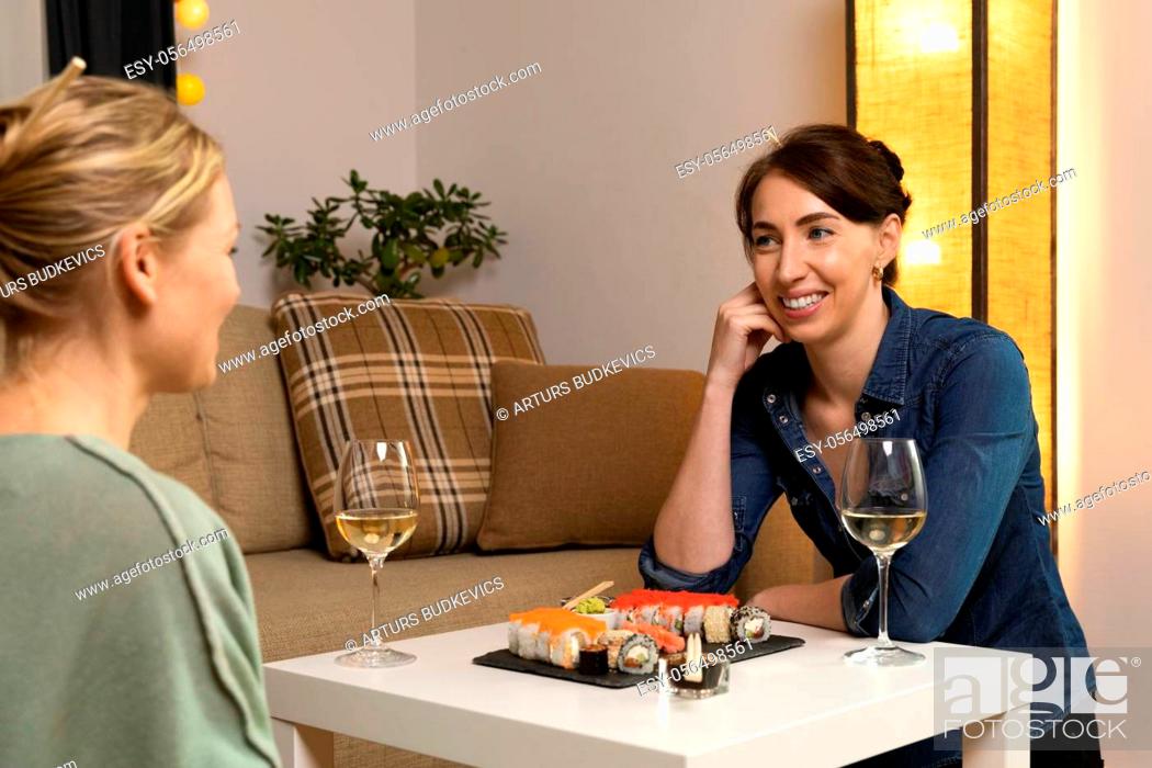 Stock Photo: Two women friends sitting by table and eating sushi. Family, friendship and communication concept.
