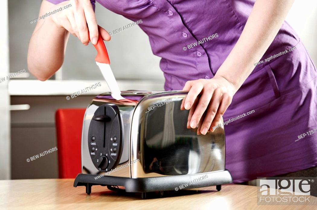 Stock Photo: Girl holding a knife in the toaster.