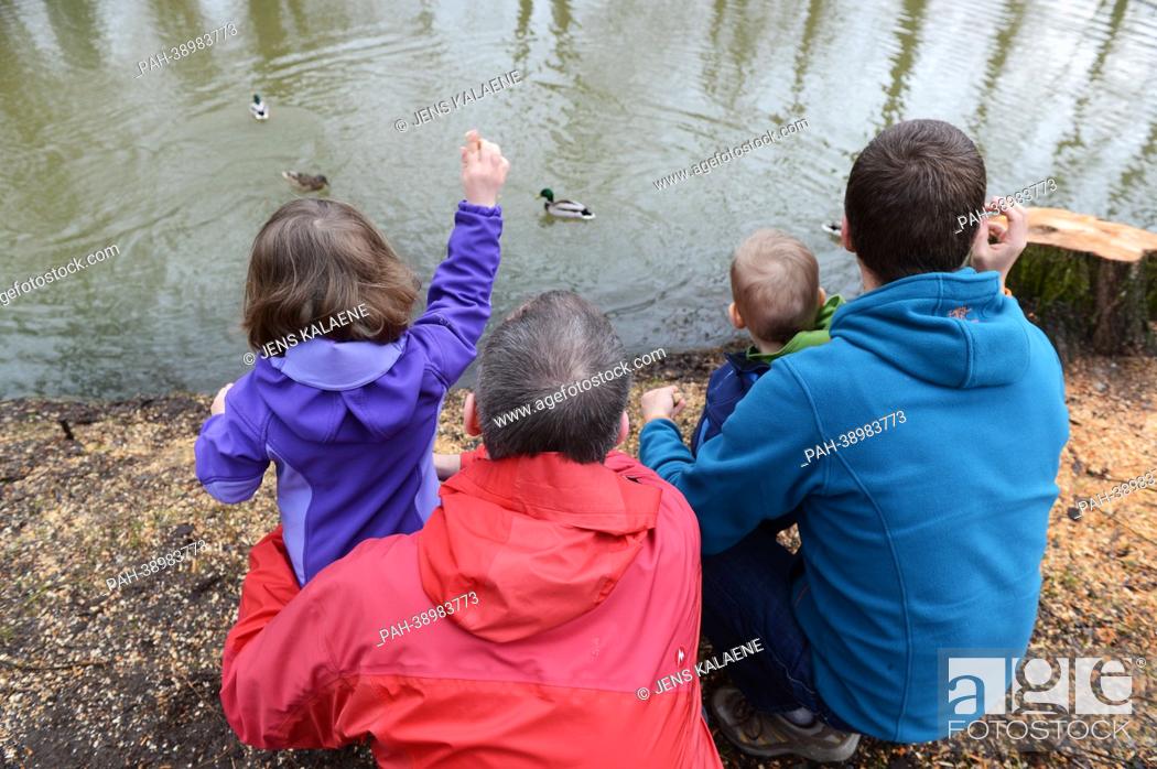 Stock Photo: Homosexual couple which lives in a same-sex partnership feeds ducks with two children on a lake in Berlin, Germany, 11 April 2013.