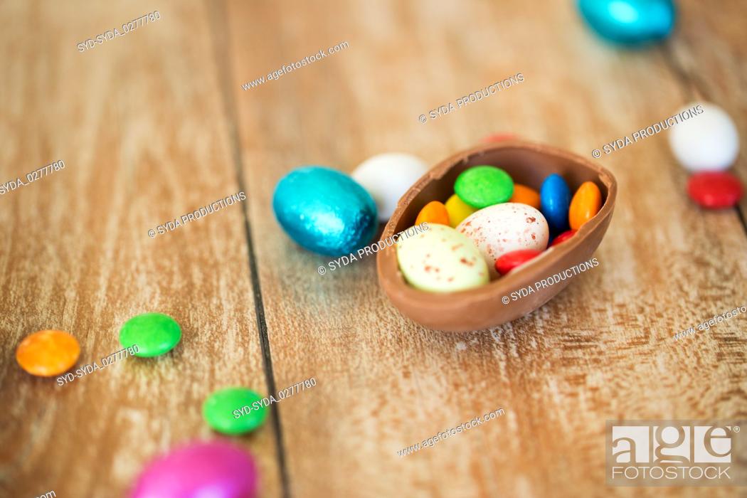 Stock Photo: chocolate easter egg and candy drops on table.