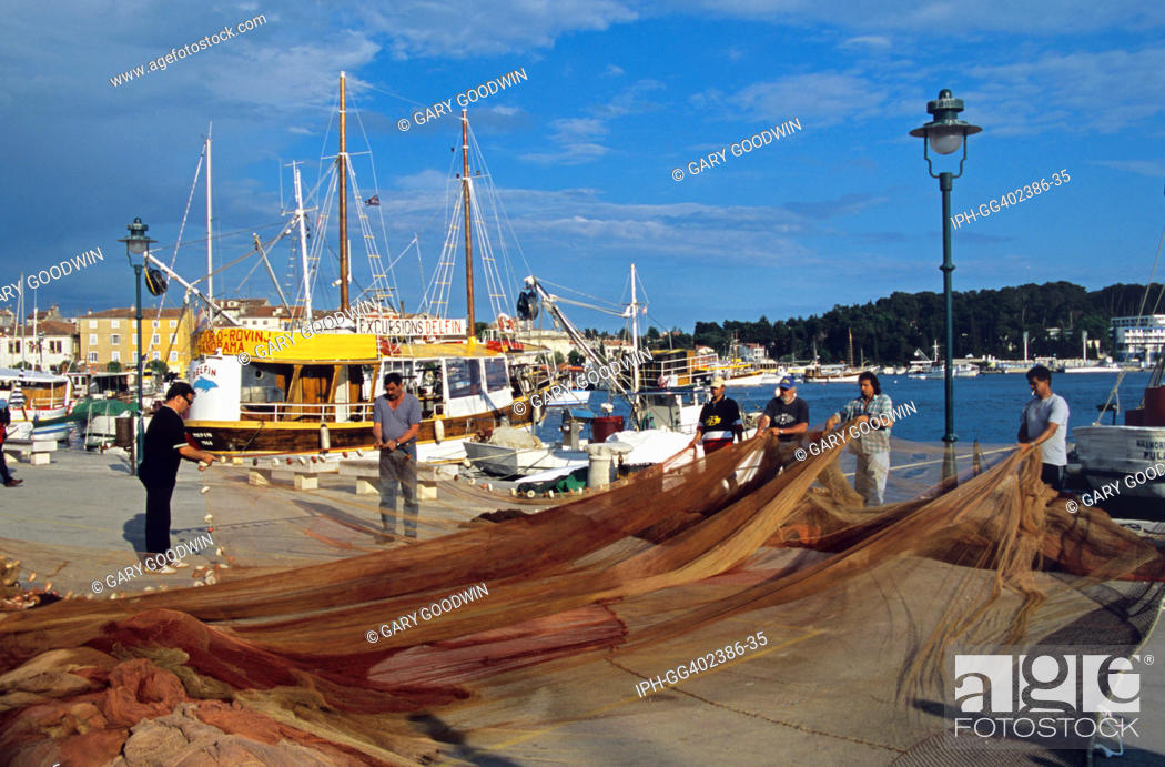 Stock Photo: Croatia - Fishermen sorting nets on the quayside in the resort of Rovinj.