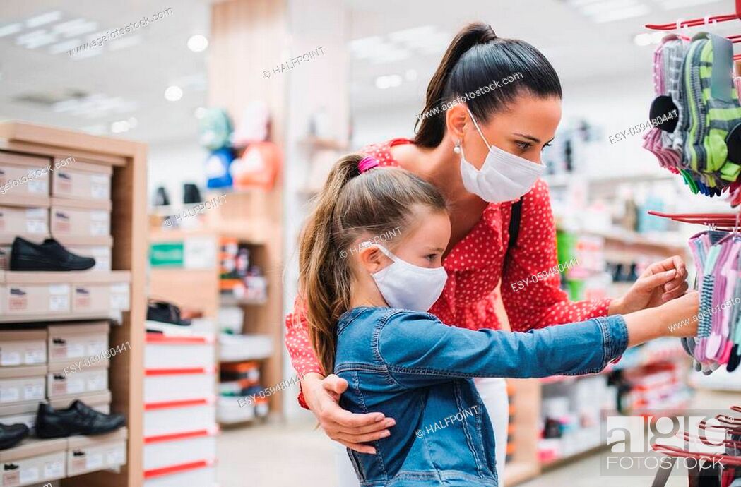 Stock Photo: Mother and small daughter with face mask shopping in shoeshop coronavirus concept.
