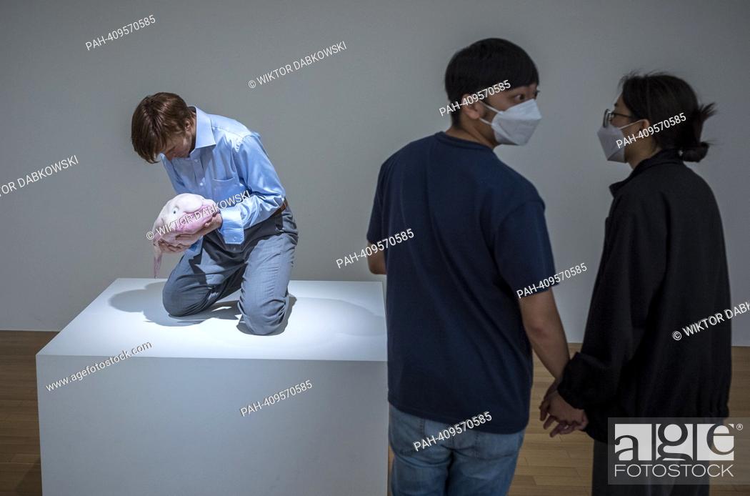 Stock Photo: People look at Eulogy a sculpture of nicely dressed man with blowfish in his hands by Patricia Piccinini during the SUPERNATURAL: Sculptural Visions of the Body.