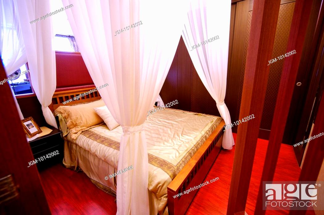 Four Poster Bed With White Curtains Tied Up At Four Corners In A