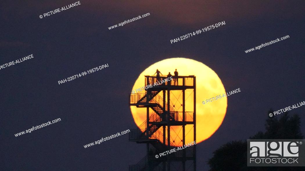 Stock Photo: dpatop - 14 July 2022, Lower Saxony, Syke: Onlookers watch the moon rise from the observation tower on the Hohe Berg. The so-called supermoon is a celestial.