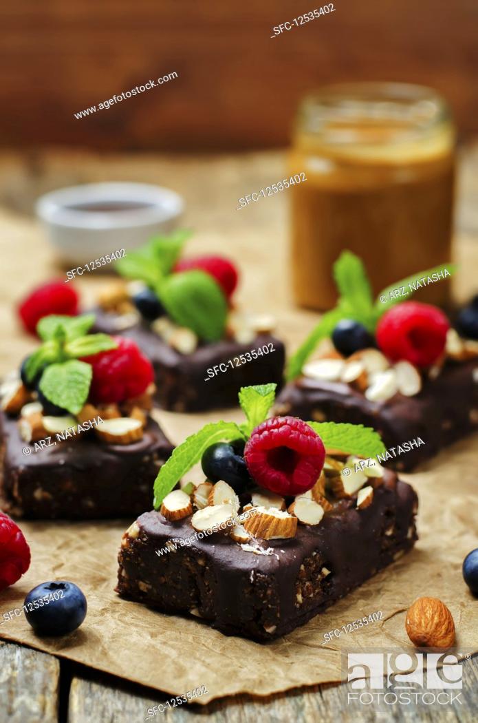 Stock Photo: Raw vegan no bake chocolate, dates and almond brownies with chocolate frosting and berries.