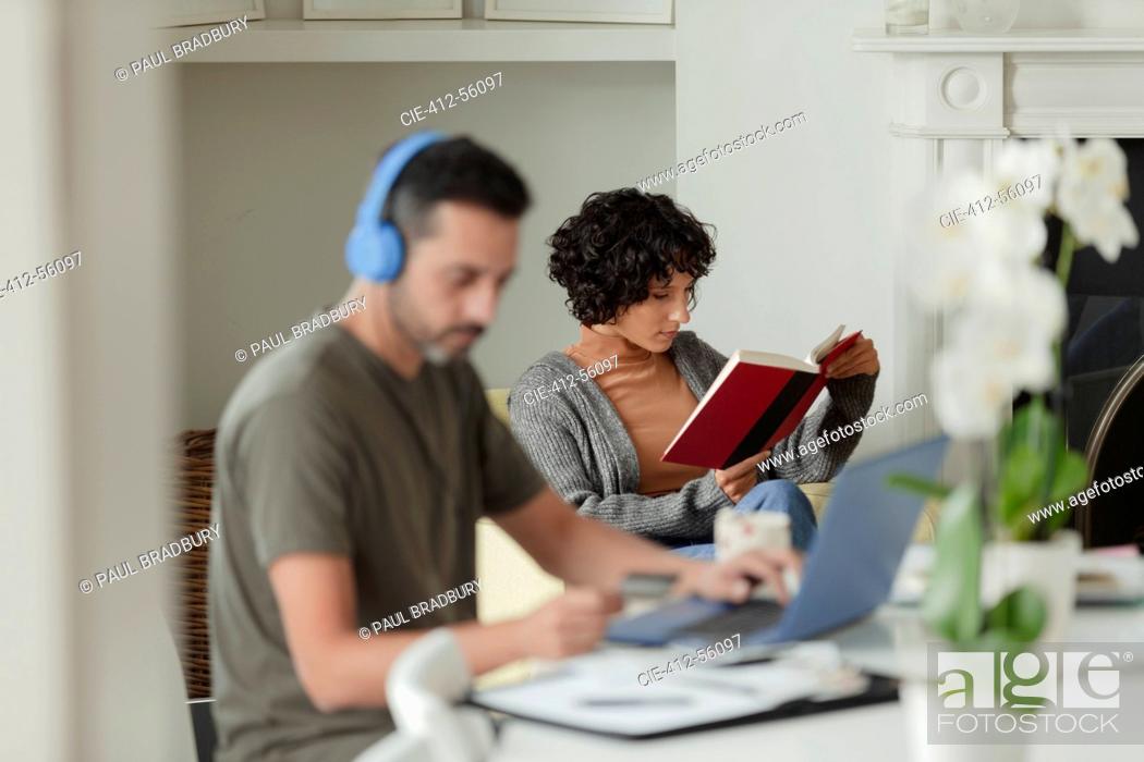 Stock Photo: Couple reading and working from home at laptop.
